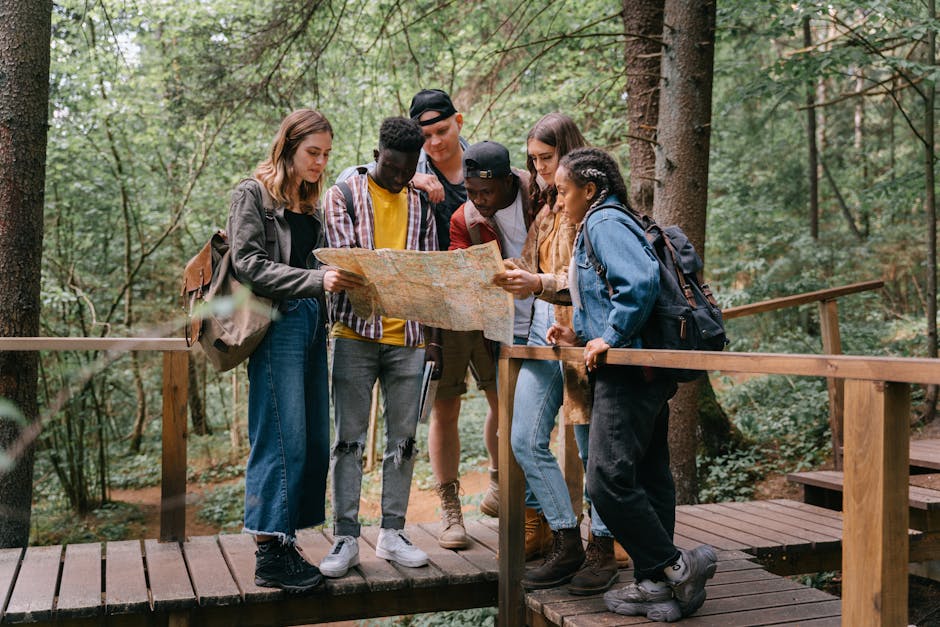 Kenai Peninsula Fishing Derby — July 3, 2026 — Group of young adults studying a map while hiking on a forest bridge.