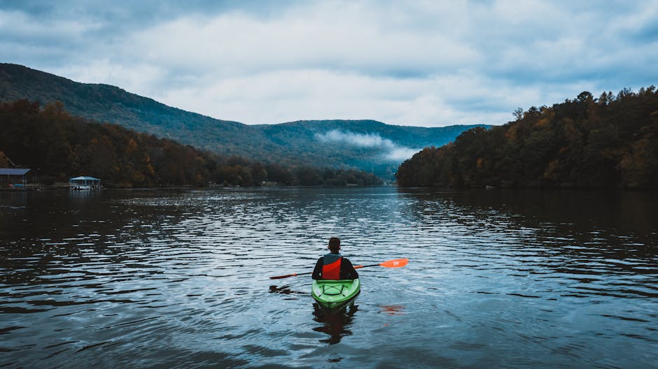 Kenai Peninsula Kayaking Meetup — May 2, 2026 — A lone kayaker paddles on a calm, misty lake surrounded by scenic mountains and autumn trees.