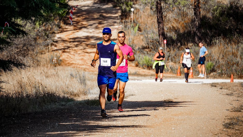 Kenai Peninsula Trail Race — June 5, 2026 — Runners competing in an outdoor marathon on a sunlit dirt road through a wooded area.
